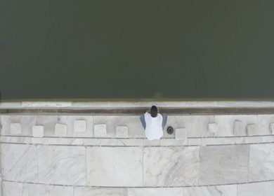 An aerial shot of a man washing his hands at a waterbody in Jama Masjid 