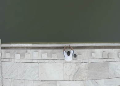An aerial shot of a man washing his hands at a waterbody in Jama Masjid 