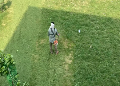 A Shot of Ground worker cutting grass with brush cutter machine in park