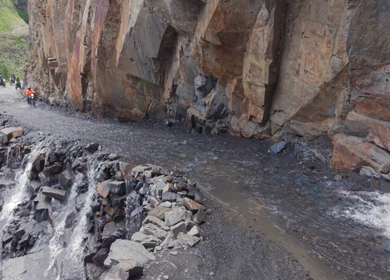 Adventure Motorcyclists Crossing Waterfall Cliff Road in Ladakh India