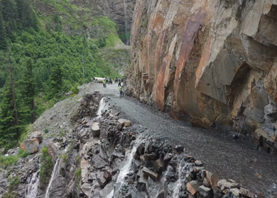 Adventure Motorcyclists Crossing Waterfall Cliff Road in Ladakh India