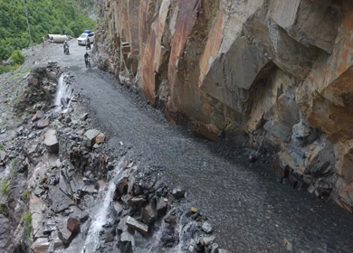 Adventure Motorcyclists Crossing Waterfall Cliff Road in Ladakh India