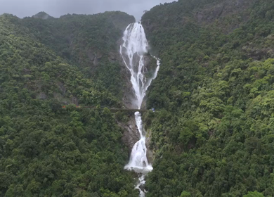 Aerial Slow motion View of Dudhsagar Waterfall with Train Crossing Bridge in Goa India