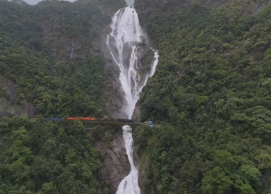 Aerial Slow motion View of Dudhsagar Waterfall with Train Crossing Bridge in Goa India