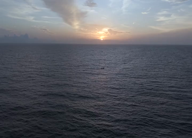 Aerial View of Sunset Over Ocean Horizon with Golden Light and Clouds in Kerala