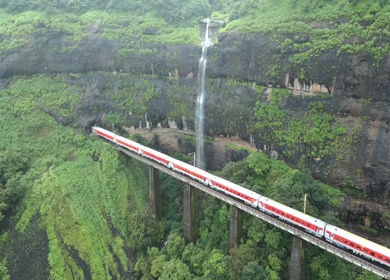 Aerial View of Train Crossing Waterfalls on Mountain Railway Bridge in Lonavala Maharashtra