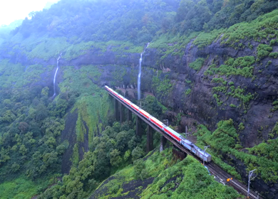 Aerial View of Train Crossing Waterfalls on Mountain Railway Bridge in Lonavala Maharashtra