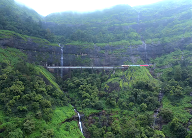Aerial View of Train Crossing Waterfalls on Mountain Railway Bridge in Lonavala Maharashtra