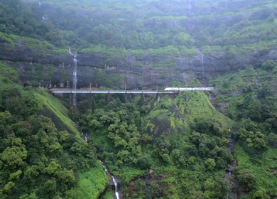 Aerial View of Train Crossing Waterfalls on Mountain Railway Bridge in Lonavala Maharashtra