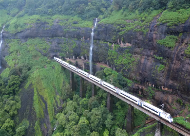 Aerial View of Train Crossing Waterfalls on Mountain Railway Bridge in Lonavala Maharashtra