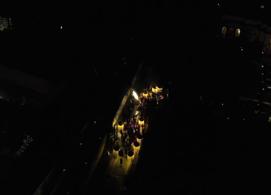 Aerial night shot of a traditional Indian wedding baraat with decorated car, dancers, and festive lights in india