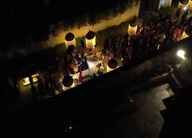 Aerial night shot of a traditional Indian wedding baraat with decorated car, dancers, and festive lights in india