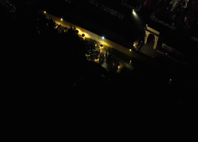 Aerial night shot of a traditional Indian wedding baraat with decorated car, dancers, and festive lights in india