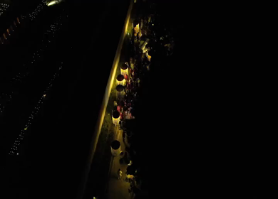 Aerial night shot of a traditional Indian wedding baraat with decorated car, dancers, and festive lights in india