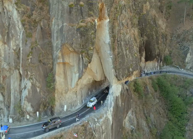 Aerial shot of car convoy passing through narrow cliff road in Kalpa Himachal Pradesh India