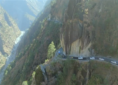 Aerial shot of car convoy passing through narrow cliff road in Kalpa Himachal Pradesh India