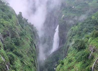 Aerial shot of waterfall in misty green mountains in Maharashtra India