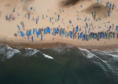 Aerial top view of fishing boats lined on sandy beach with waves in Kovalam Kerala India