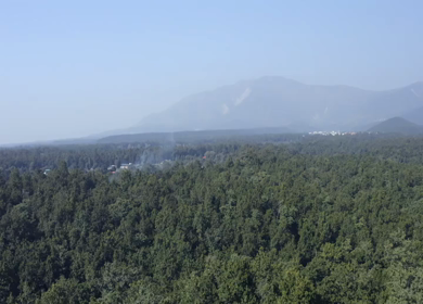 Aerial view of forest covered mountains under a blue sky with clouds in Uttarakhand, India