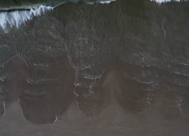 Aerial view of ocean waves washing onto a sandy beach in Phuket, Thailand