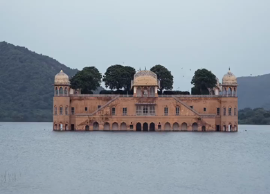 A shot of Jal Mahal palace on Man Sagar Lake in Jaipur, surrounded by hills and water