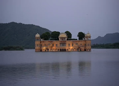 A shot of Jal Mahal palace on Man Sagar Lake in Jaipur, surrounded by hills and water