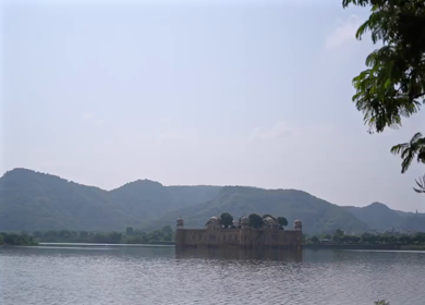 A shot of Jal Mahal palace on Man Sagar Lake in Jaipur, surrounded by hills and water