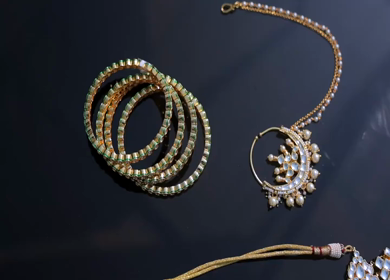A slow motion shot of elegant Indian bridal jewelry featuring an ornate necklace, bangles, earrings, and headpiece