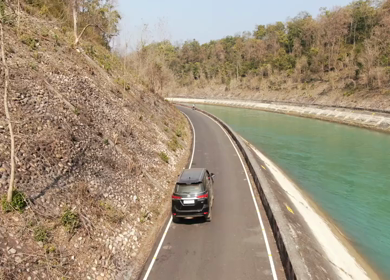 An aerial drone of a car being driven beside a road in India