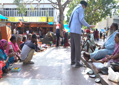 A static shot people distributing prasad to beggars outside Hanuman Mandir