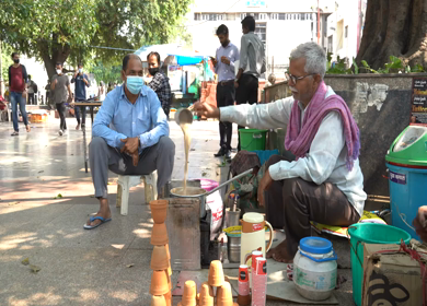 A static shot of an old man making tea outside Hanuman Mandir