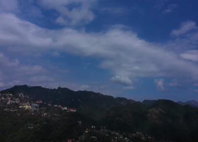 An aerial shot of the Himalayan Hilltop surrounded by Greenery and Blue Sky in Mussorrie,Uttarakhand,India