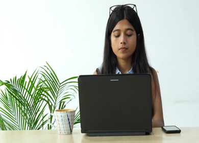 Shot of an Indian Girl Working on her laptop and sipping coffee in office