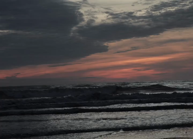 Slow motion shot of ocean waves at the beach in Phuket, Thailand during a calm evening with soft sunset light