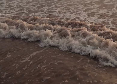 Slow motion shot of gentle ocean waves rolling onto the beach in Phuket, Thailand