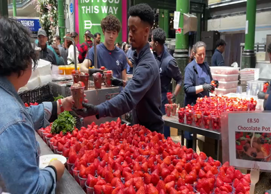 19th June 2024 : Street food vendor serving strawberries with Chocolate at Borough market in London