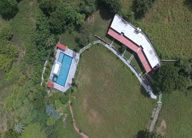 Top aerial view of luxury swimming pool surrounded by green forest landscape