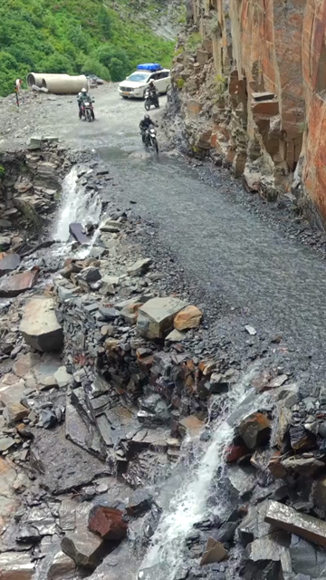 Vertical Aerial View of Adventure Motorcyclists Crossing Waterfall Stream in Ladakh