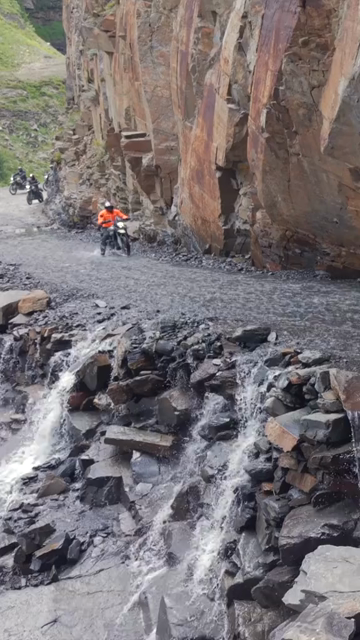 Vertical Aerial View of Adventure Motorcyclists Crossing Waterfall Stream in Ladakh