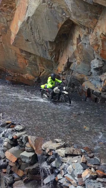 Vertical Aerial View of Adventure Motorcyclists Crossing Waterfall Stream in Ladakh