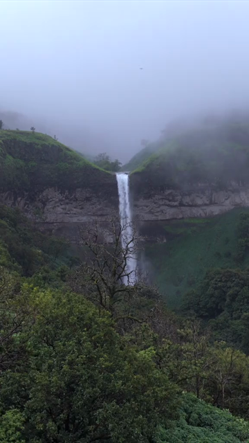 Vertical Aerial View of Waterfall in Misty Green Hills of Maharashtra
