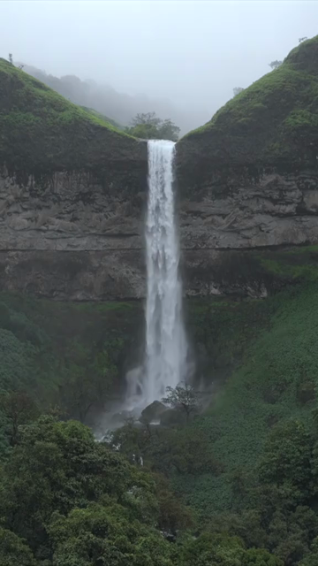 Vertical Aerial View of Waterfall in Misty Green Hills of Maharashtra