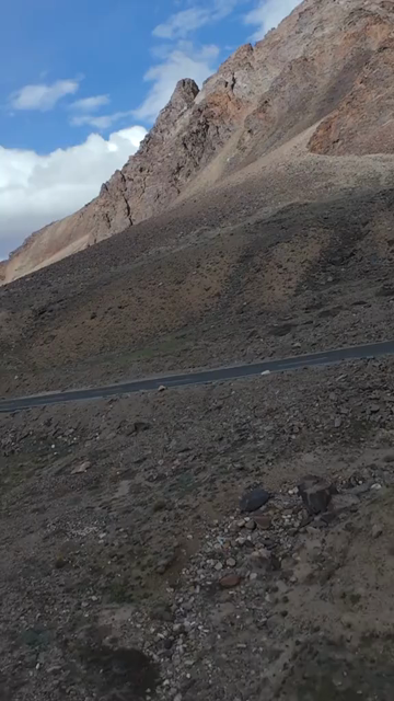Vertical FPV Drone View of Adventure Motorcyclists Riding Through Snowy Mountain Pass in Ladakh