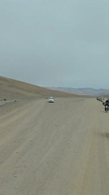 Vertical FPV Drone View of Adventure Motorcyclists Crossing Desert Plains in Ladakh