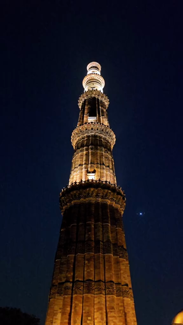 Vertical Night View of Qutub Minar with Airplane Flying Over Delhi India
