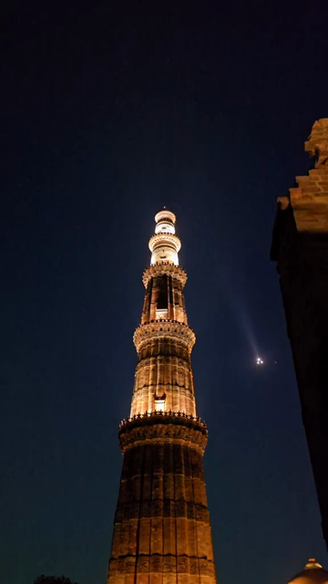 Vertical Night View of Qutub Minar with Airplane Flying Over Delhi India