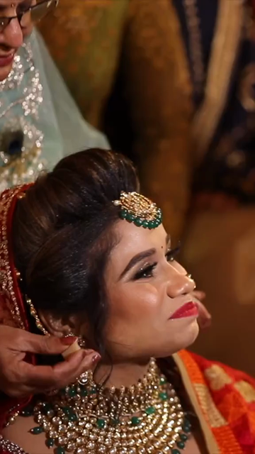 Vertical Shot of Groom's Mother Feeding Sweets to Bride During Indian Wedding